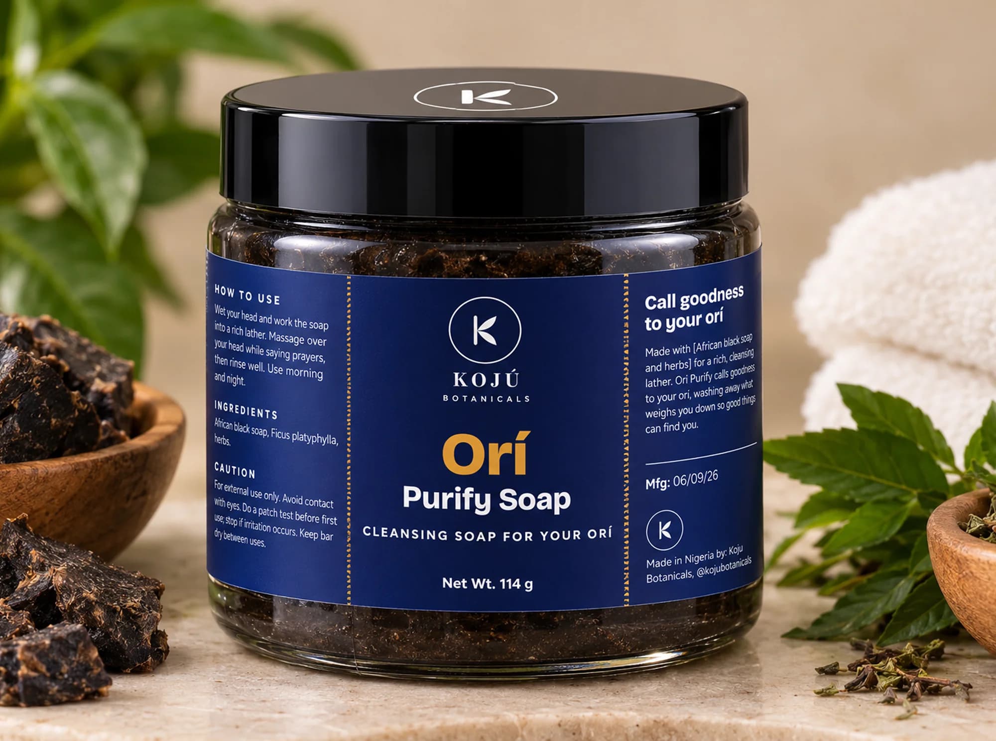 A jar of Orí Purify Soap surrounded by African black soap and fresh herbs